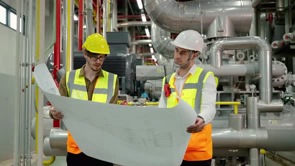 Engineer and Foreman are discussing the plant layout on the blueprint in the factory boiler room
