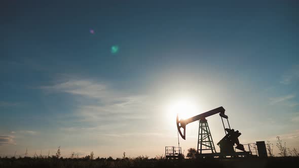 Silhouette of Working Oil Pump From Oil Field at Sunset alt