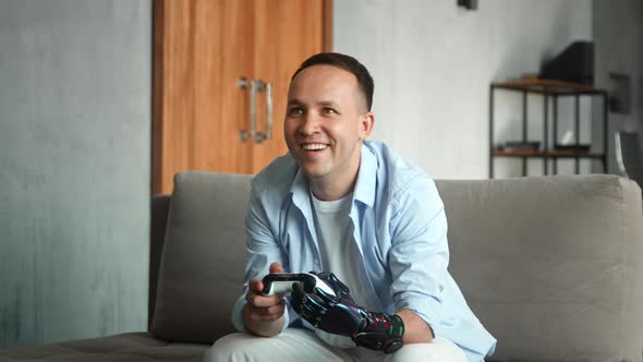 Amazed man with high tech hand prothesis plays console game holding joystick alt