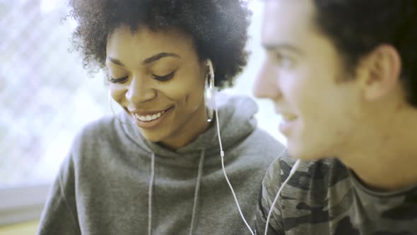 Teenage boy and girl sharing earphones and listening to music