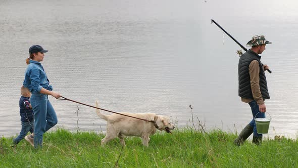 Family with a Dog on Vacation Go Fishing Near the Lake alt