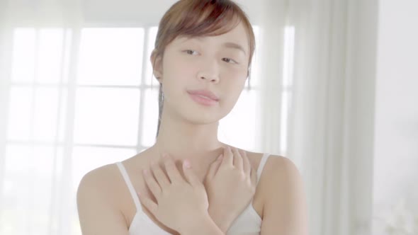 Beautiful young asian woman looking mirror and apply lotion sunscreen with neck. alt