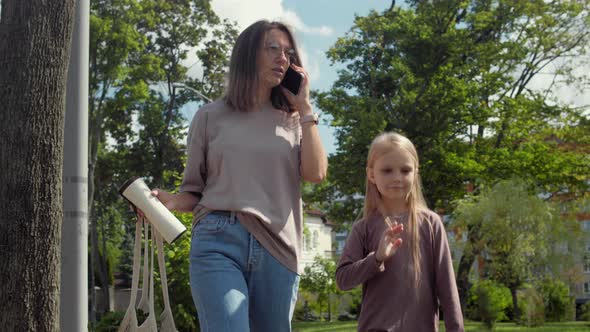 Woman with kid walks outside with mesh string knitted shopping bag alt