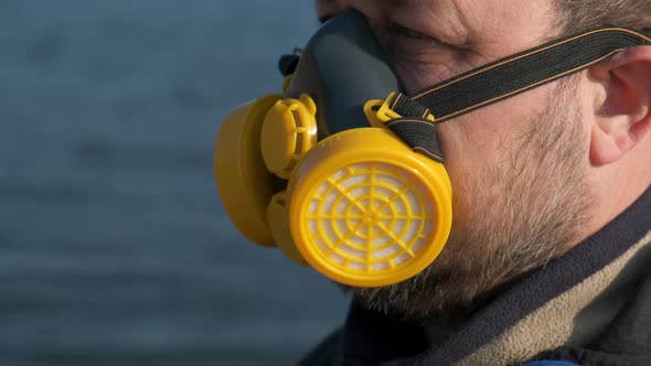 A bearded man in a respirator on the lake in the Park.