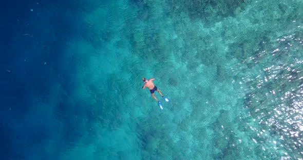 Young man snorkel over clear sea water near shore of tropical island, watching fish swim through cor alt