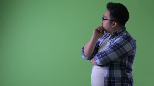 Profile View of Happy Young Overweight Asian Hipster Man Thinking alt