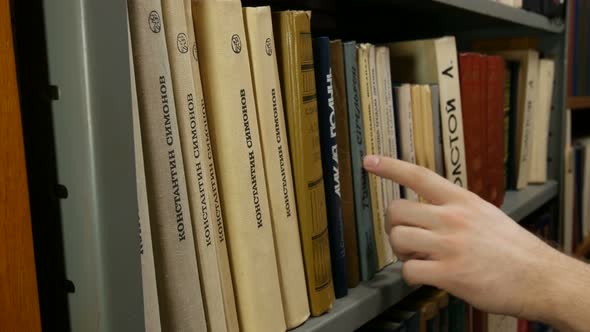 Man In The Library Picks A Book From The Shelf