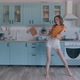 A Beautiful Woman in White Shorts is Relaxing at Home Dancing in the Kitchen - VideoHive Item for Sale