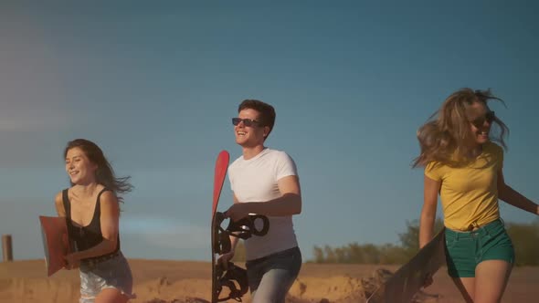 Multiracial Friends Running on the Sand with Snowboard or Sandboard, Smiling and Getting Pleasure. A alt