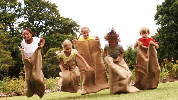 Kids having a sack race in park alt
