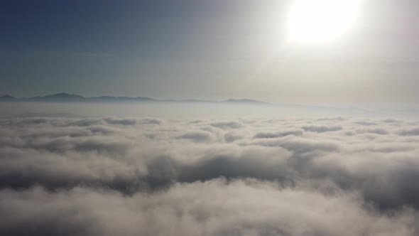 Aerial Bird View Moving Low Above the Clouds Flight Backwards Away From Bright Sun and Crisp Blue alt