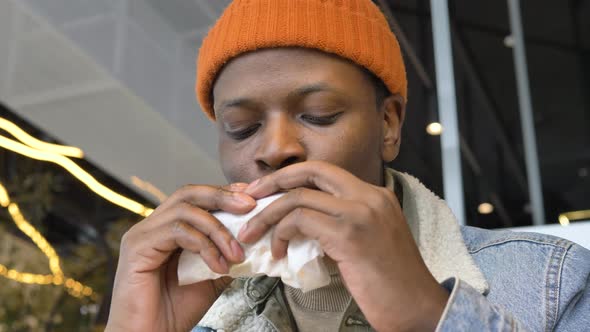 African American Guy in Hat and Jacket Tastes New Burger alt