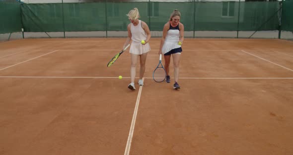 Two Attractive Girls in Sportswear Going Side By Side on Tennis Court After Successful Match