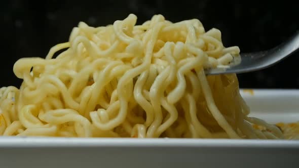 A Very Closeup of a Metal Fork Winding Instant Noodles Around Itself