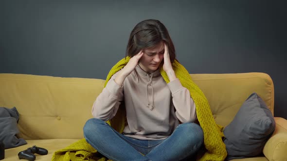 Sick Girl Sits on Sofa Wrapped in Plaid Suffering From Headache or Migraine