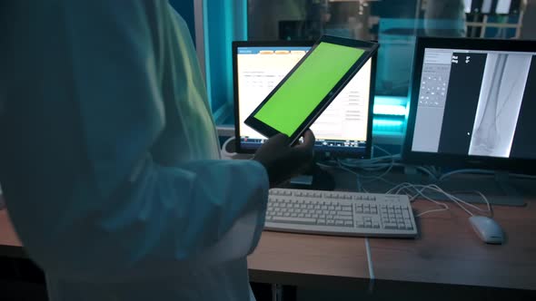 Doctor with a Tablet with a Green Screen Watching the Operation From the Control Room alt