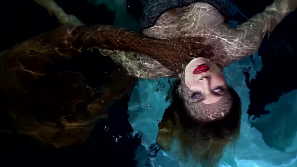 Black Man Is Drowning Beautiful Woman in Water of Swimming Pool, Holding Hand on Her Neck alt