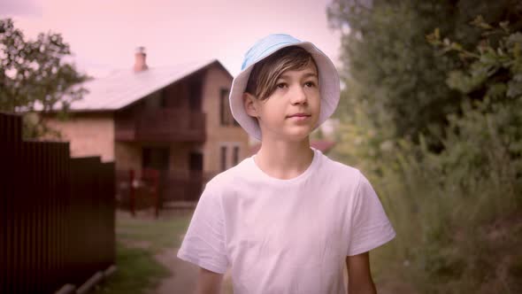 Funny Boy in a Hat Walking Along a Village Road Looking Around Cinematic Shot