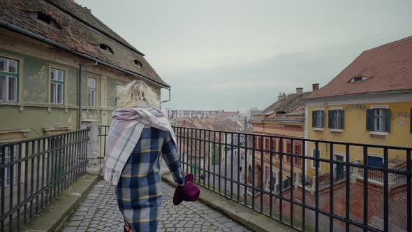 Woman reaching the top point of the old city with paint peeled walls buildings. alt