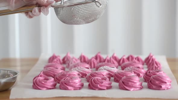 Sprinkle icing sugar on a pink dessert