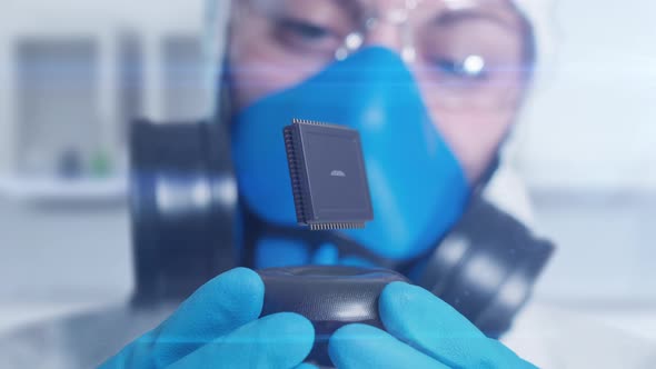 a scientist in a clean room holds a newly developed chip for computing alt