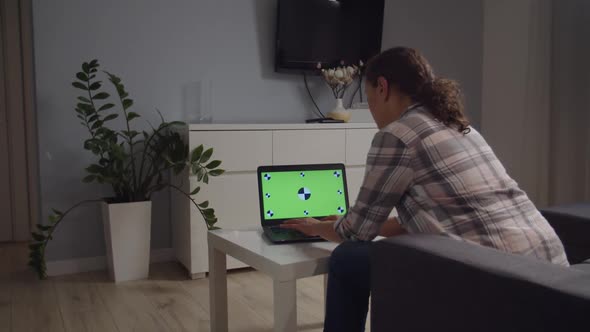 Side Moving Camera Freelancer Using Laptop with Green Screen Indoors alt