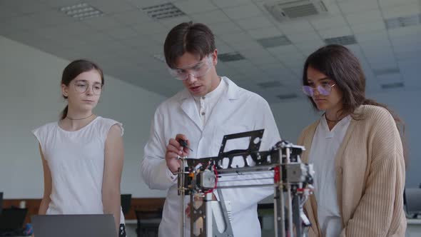 Teacher and Students Stand Above the 3D Printed Machine alt