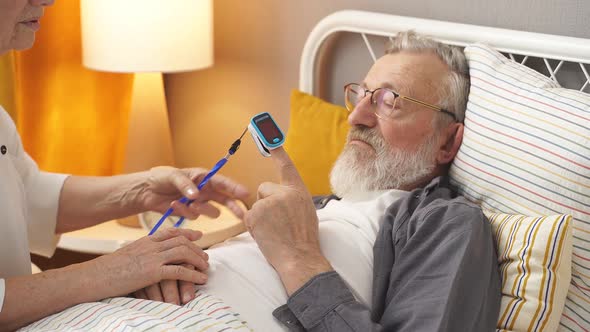 Senior Woman Apply at Sick Husband's Fingertip Pulse Oximeter Check Pulse Rate alt