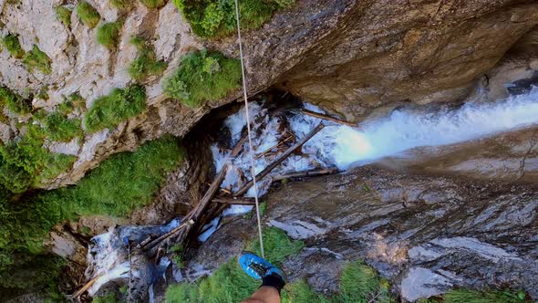 A man walking on a cable that goes across a waterfall. You can not see any security line so it seems alt