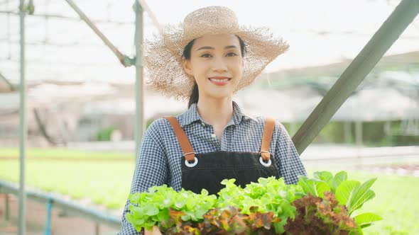 Portrait of Asian young woman farmer hold basket of vegetables in farm. alt