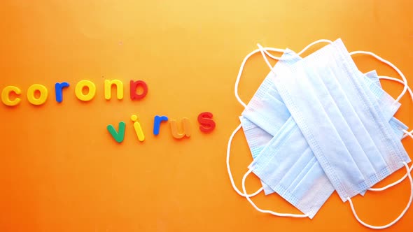 Close Up of Blue Surgical Masks and Colorful Plastic Alphabet on Orange alt