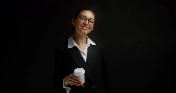 Brunette in Glasses and Office Clothes Drinks Coffee From a White Paper Cup