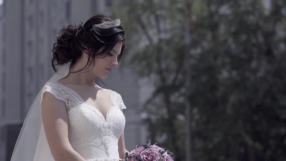 Slow Motion Bride with Tiara on Hair Looks at Bouquet alt