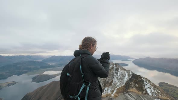 Hiker taking photos at the top of Roy's Peak in Wanaka, New Zealand alt