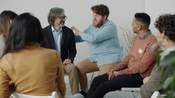 Bizarre Man with Strange Behavior Talking and Gesturing at Support Meeting with People alt