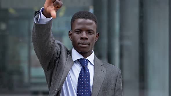 Young African businessman thumbs down. Refused, bankruptcy- slow motion alt