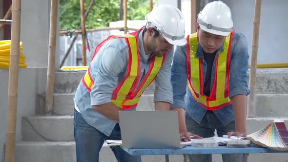 Young Asian engineers and caucasian engineer colleagues at site inspector and discuss together alt