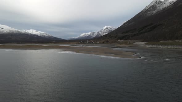 Flying Over Calm Waters Of Fjord With Snowy Mountains In Breivikeidet, Northern Norway. - aerial alt