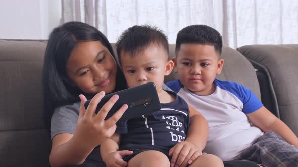 A Young Girl Shows Her Little Brothers A Video On Her Phone alt