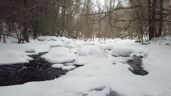 Low flying drone above a snowy river in winter alt