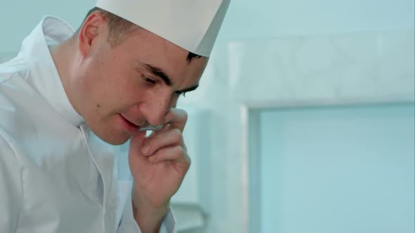 Male Chef in White Uniform Cooking and Talking on the Phone alt