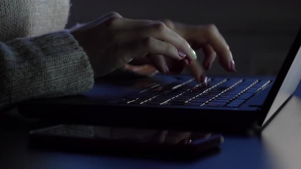 Slow motion shot of woman using laptop at home in the evening