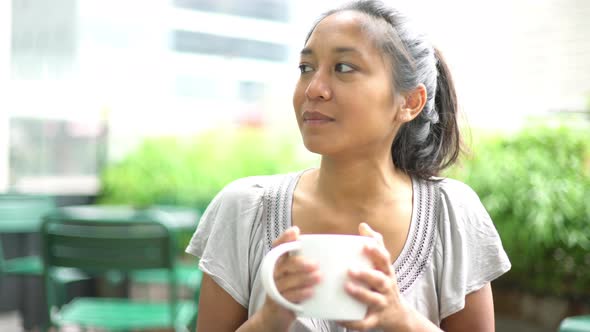 Woman drinking coffee in outdoor cafe
