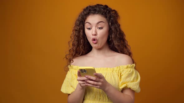 Young Woman Using Smartphone Against Yellow Background
