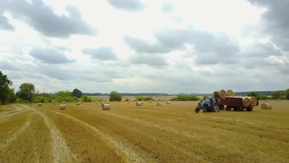 Tractor Loading Bales. Tractor loading bales of straw in the field alt