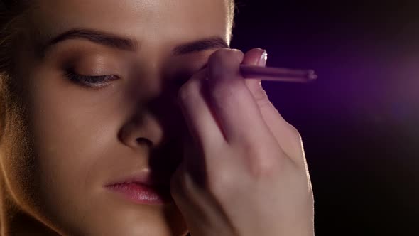 Applying Makeup on Female Face. Professional Makeup. Black. Closeup alt