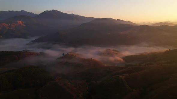 4K aerial view over a misty mountainous area. The great golden sun in the morning alt
