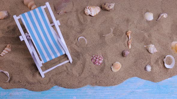 Sun Lounger and Seashells on the Sand on a Blue Background