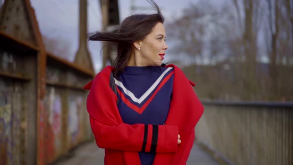 a Brunette with Bright Lipstick and a Piercing on Her Face Is Walking on a Railway Bridge. She's alt