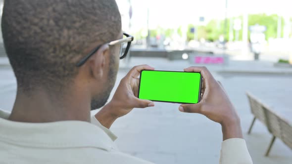 African Man Watching Smartphone with Green Screen Outdoor alt